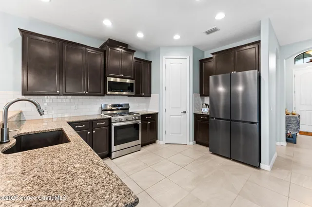 a kitchen with stainless steel appliances granite countertop a refrigerator stove and oven