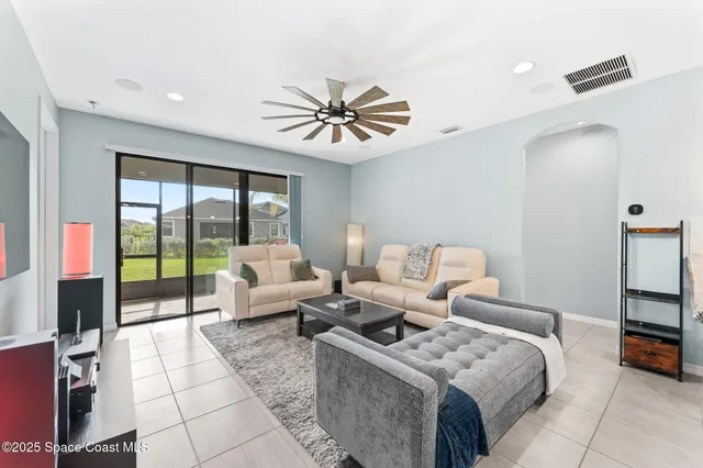 a living room with furniture two large window and a chandelier