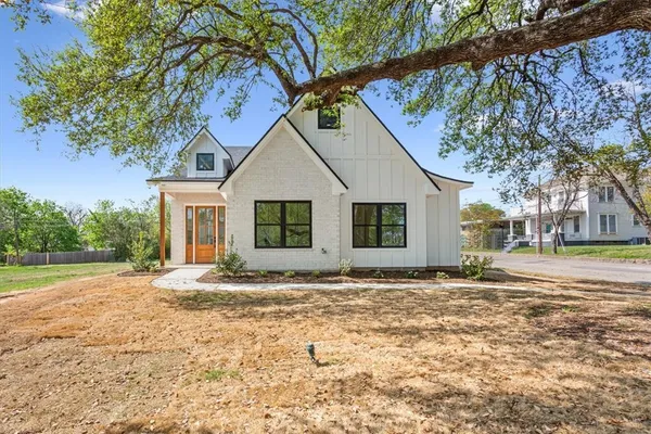 a view of a yard in front of a house with large trees