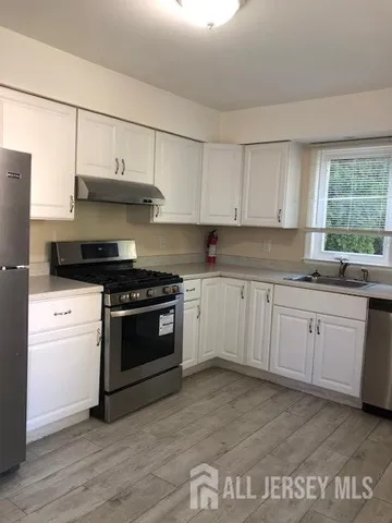 a kitchen with stainless steel appliances granite countertop a stove a sink and white cabinets