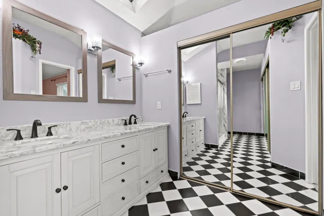 a bathroom with a double vanity sink a mirror a toilet and a shower