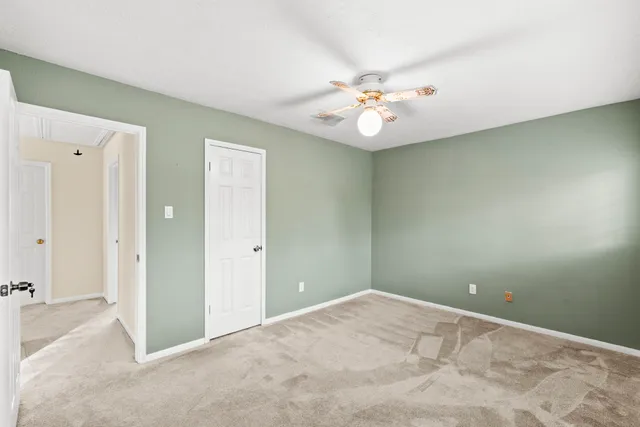 an empty room with a chandelier fan and a bathroom