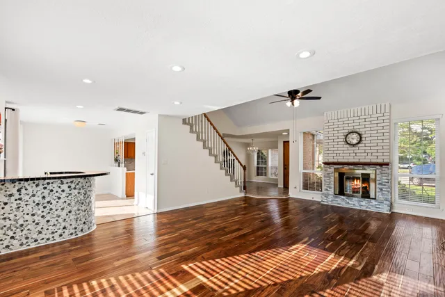 a view of an empty room with wooden floor fireplace and a window