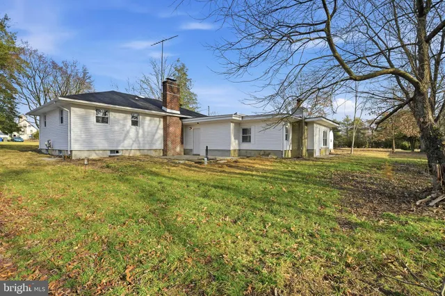 a white house that has a big yard with large trees