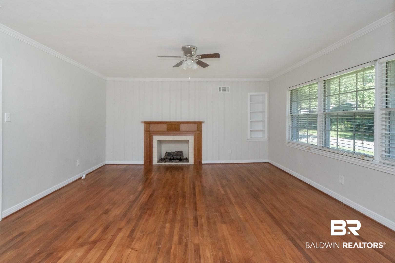 2105 Upham Court Mobile, AL 36607 - Photo 7 of 32 Unfurnished living room with a fireplace, dark wood finished floors, a ceiling fan, and ornamental molding