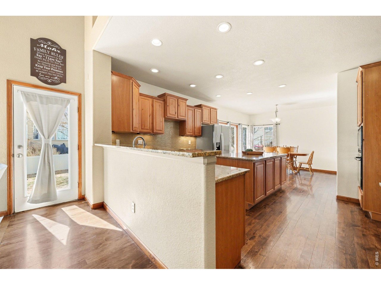 5507 Morgan Way Frederick, CO 80504 - Photo 14 of 45 a living room with stainless steel appliances kitchen island granite countertop a refrigerator a sink a stove and oven with wooden floor