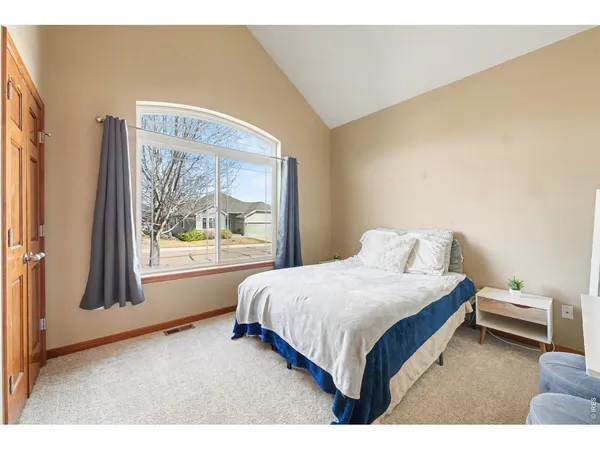 a bedroom with a bed lamp and a large window