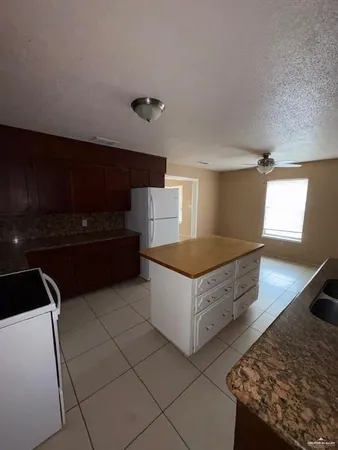 a living room with stainless steel appliances kitchen island granite countertop a refrigerator and a stove top oven