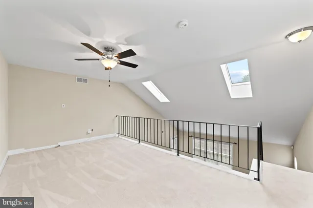 an empty room with ceiling fan and window