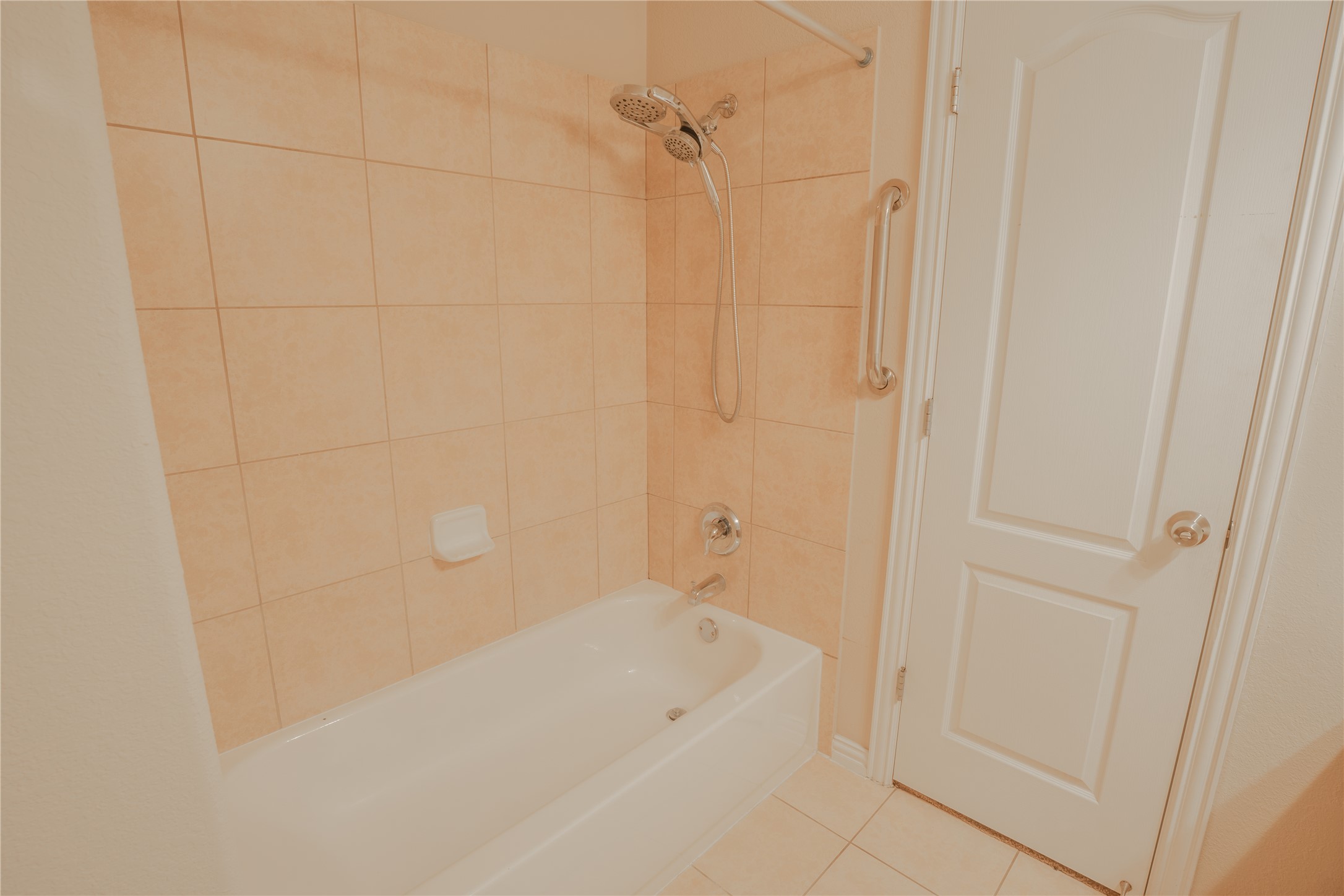 403 Tascate Street Georgetown, TX 78628 - Photo 20 of 26 The bathroom features a tiled shower/tub combination with a convenient grab bar for accessibility.