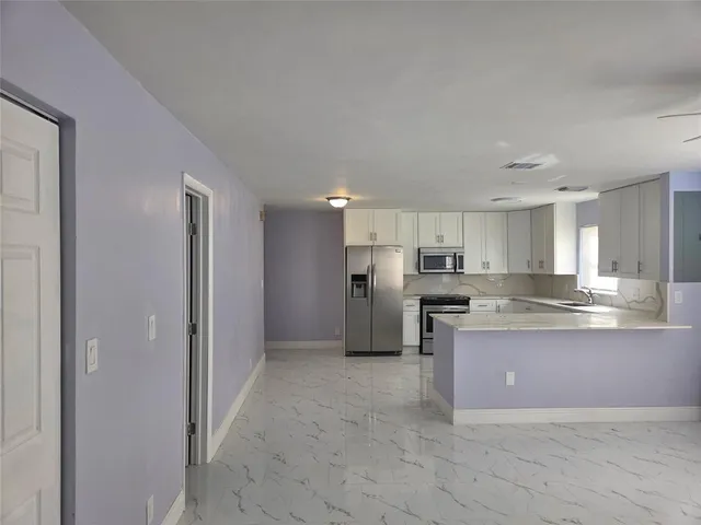 a kitchen with kitchen island granite countertop white cabinets and stainless steel appliances