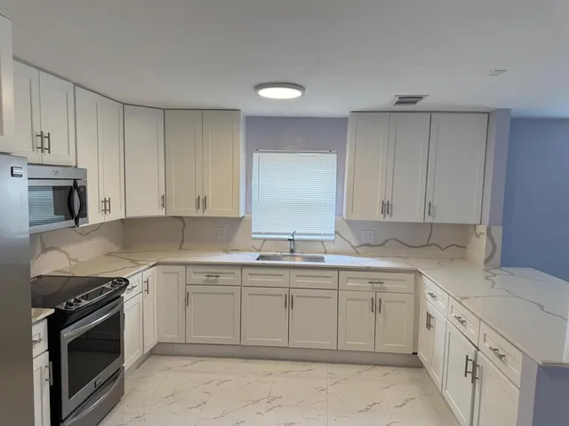 a kitchen with cabinets stainless steel appliances and a sink
