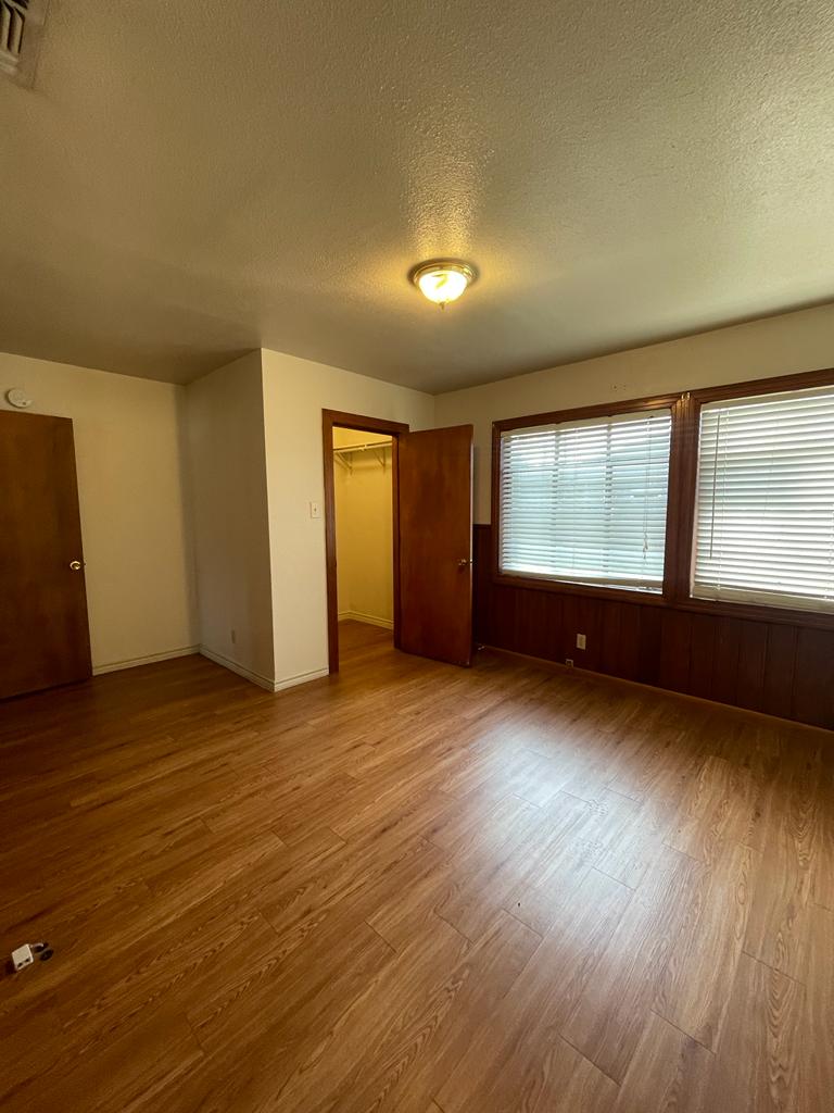 108 Austin Street, Unit B Kyle, TX 78640 - Photo 13 of 14 A well-lit bedroom features durable laminate flooring and practical window blinds for comfort and privacy.