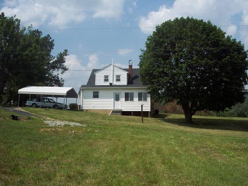 9890 Stewartsville Road Goodview, VA 24095 - Photo 2 of 16 a front view of a house with a garden and trees