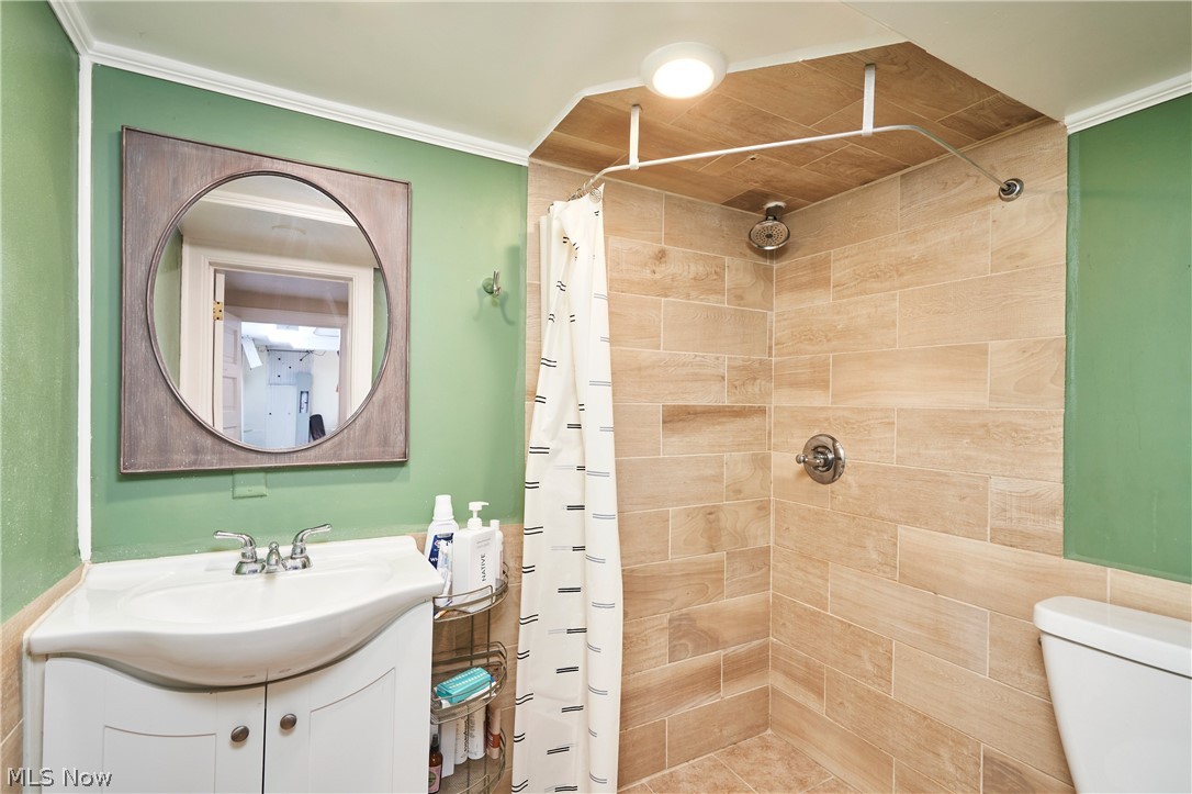 183 Overwood Road Akron, OH 44313 - Photo 28 of 34 Bathroom featuring an integrated shower with wood-finish tile, a built-in shower niche, and a circular mirror with a wood-look frame