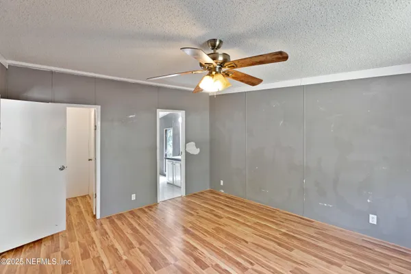 a view of a big room with wooden floor and a chandelier fan