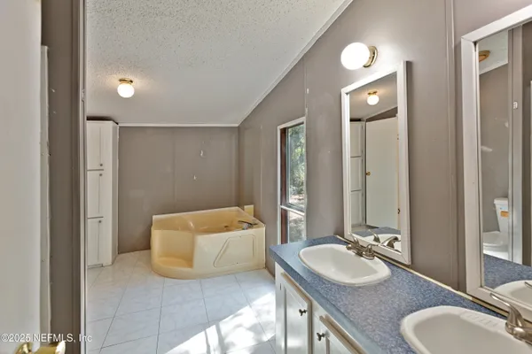 a bathroom with a granite countertop double vanity sink a mirror and a bathtub