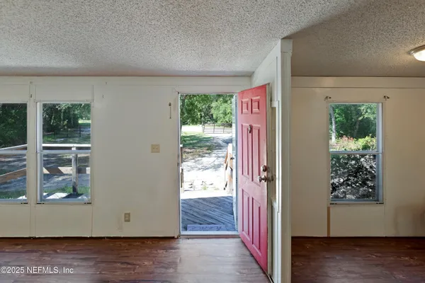 a view of a hallway with wooden floor and windows