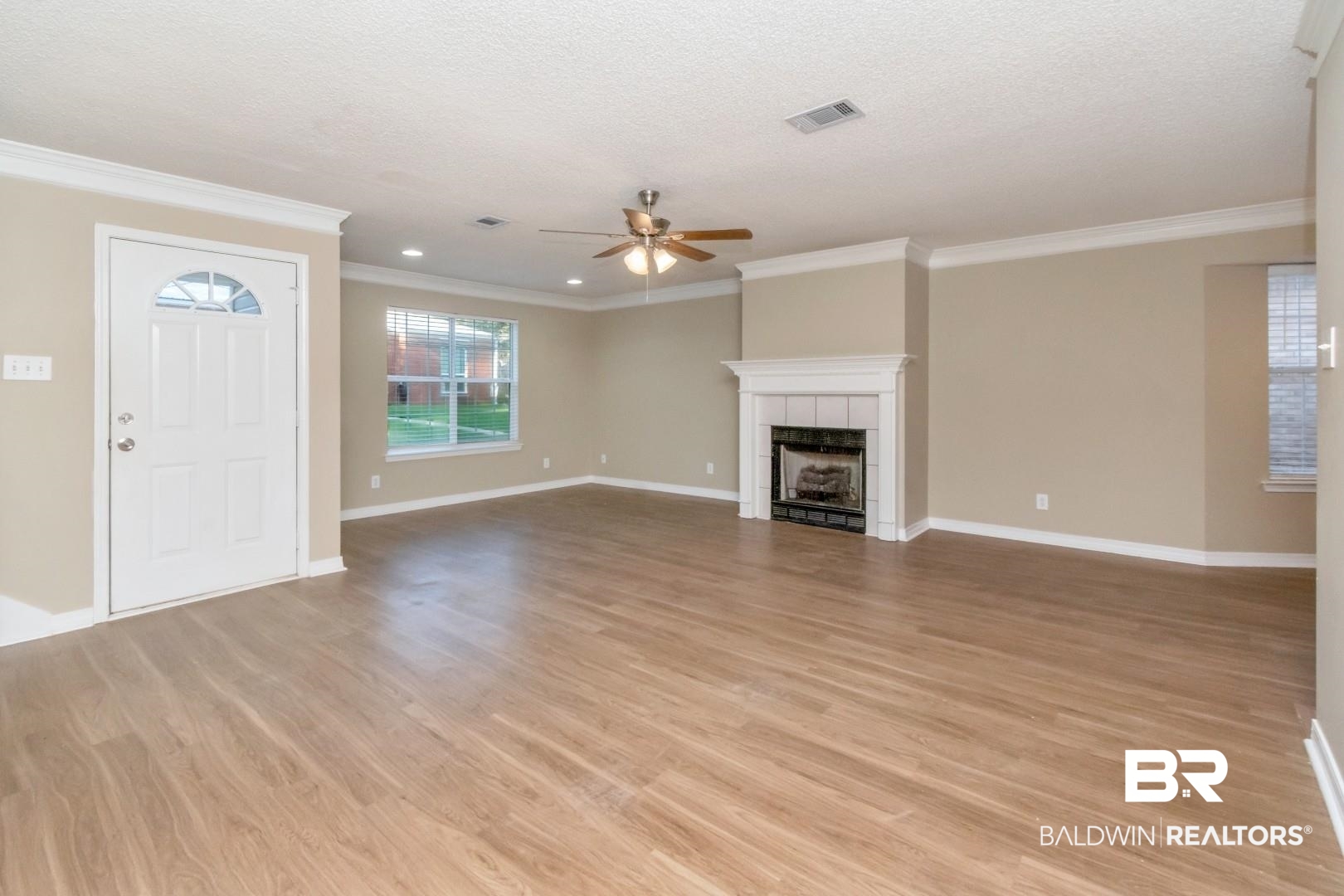 6482 Cedar Bend Court Mobile, AL 36608 - Photo 4 of 26 Unfurnished living room featuring light wood-style floors, a tile fireplace, crown molding, a textured ceiling, and a ceiling fan