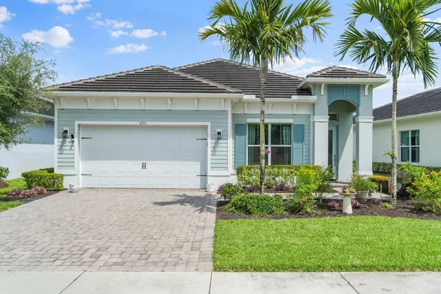 front view of a house with a yard and palm trees