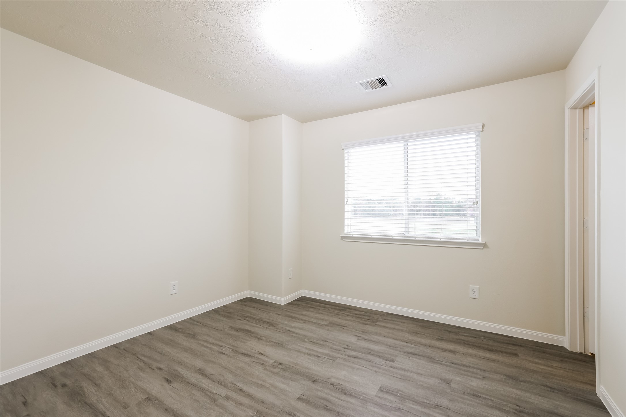12431 Roy Mix Bohn Lane Houston, TX 77044 - Photo 8 of 13 an empty room with wooden floor and windows