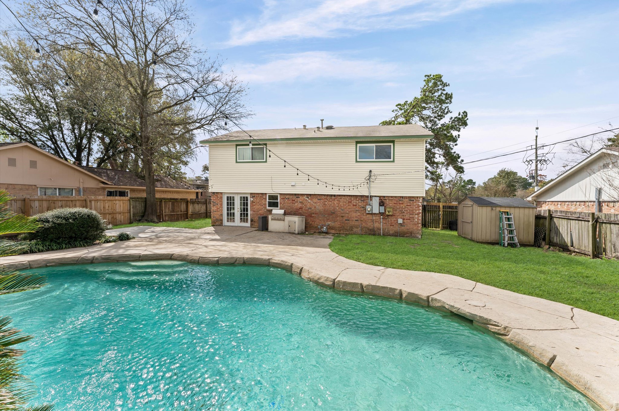 9810 Charter Ridge Drive Houston, TX 77070 - Photo 22 of 28 This backyard features a spacious pool with surrounding patio space, perfect for entertaining. The two-story home has a brick and siding exterior. There’s ample lawn area and a storage shed, all enclosed by a privacy fence, creating a serene outdoor setting.