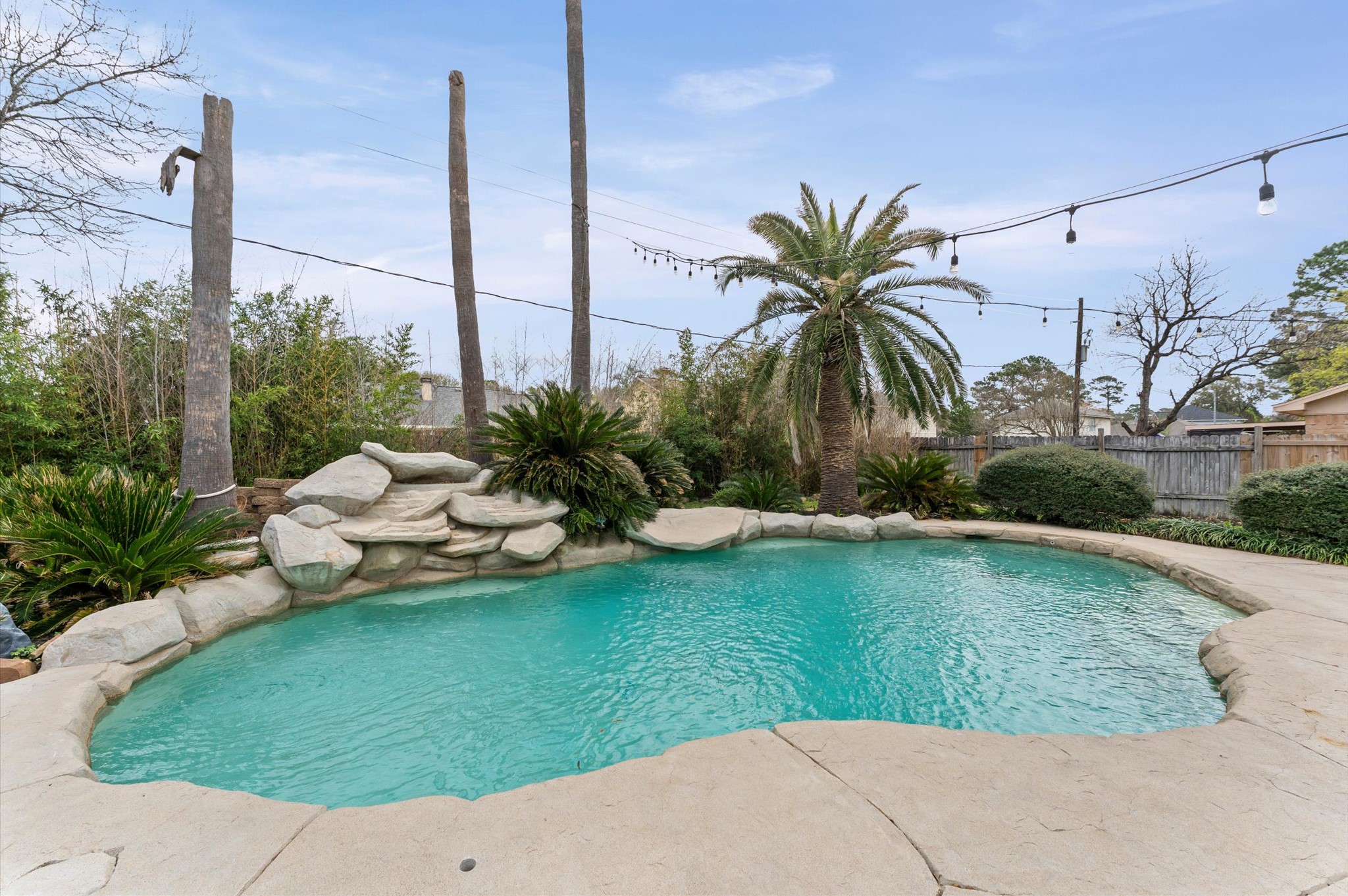 9810 Charter Ridge Drive Houston, TX 77070 - Photo 23 of 28 This backyard oasis features a beautifully landscaped pool with rock accents and lush greenery, offering a serene and private retreat.