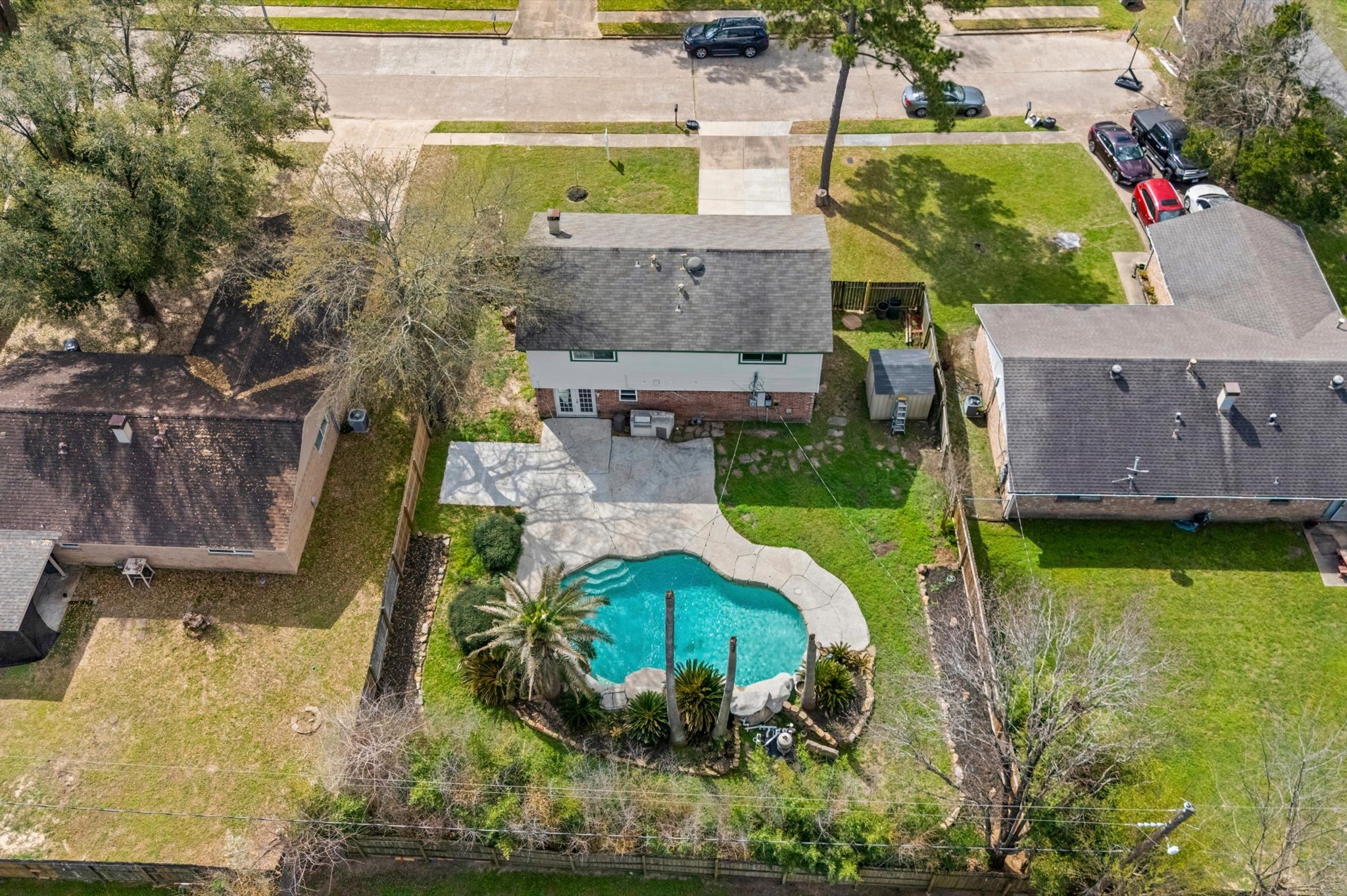 9810 Charter Ridge Drive Houston, TX 77070 - Photo 26 of 28 This aerial view shows a charming two-story home with a spacious backyard featuring a uniquely shaped pool surrounded by greenery. The property is set in a suburban neighborhood with tree-lined streets and well-maintained lawns, offering a serene and inviting atmosphere.