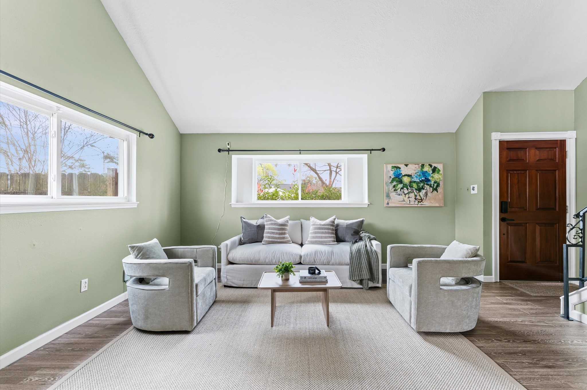 9810 Charter Ridge Drive Houston, TX 77070 - Photo 4 of 28 This living room features a high ceiling and soft green walls, creating an airy and inviting atmosphere. Large windows bring in natural light, while a wooden door adds warmth.
