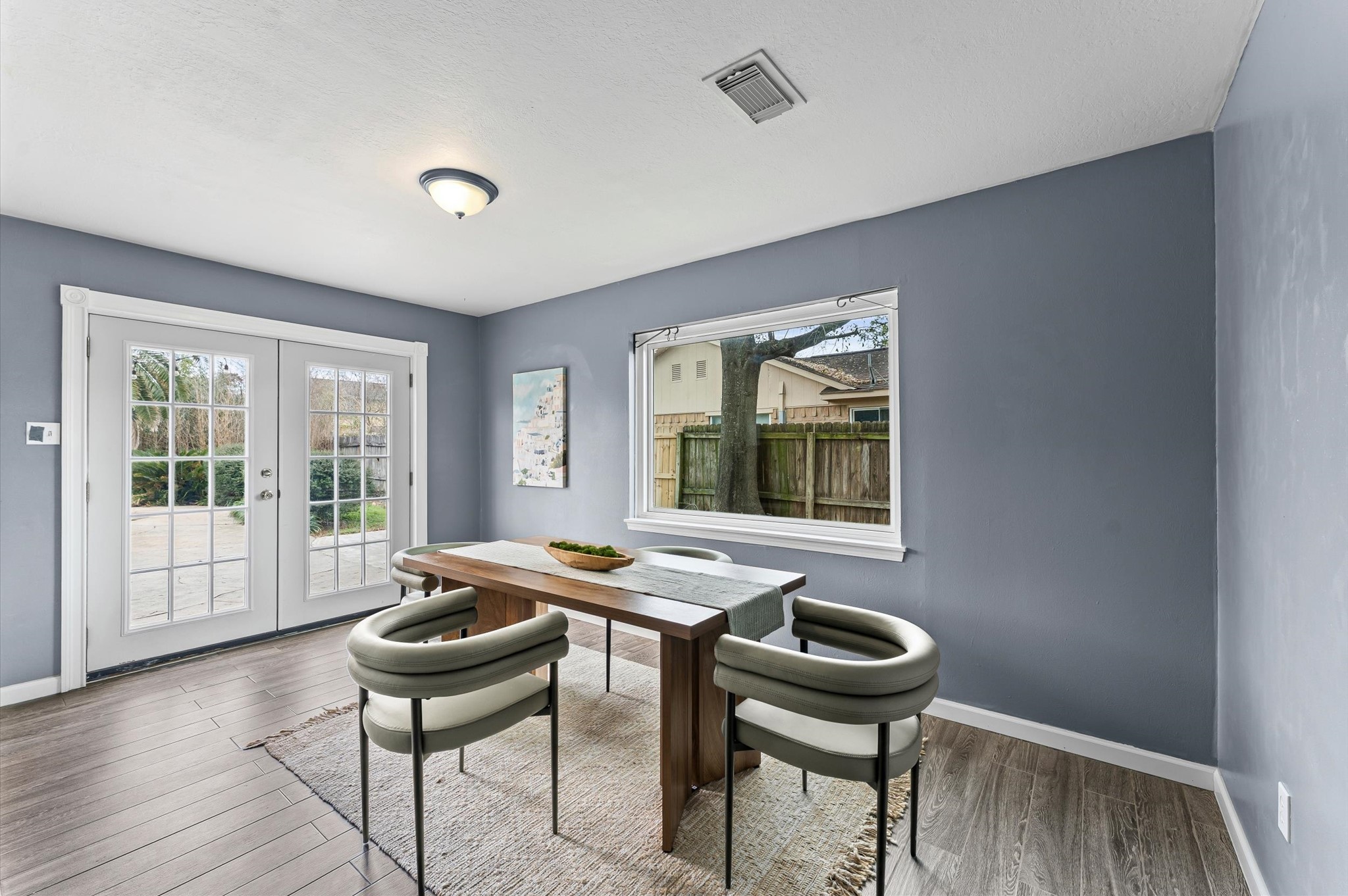 9810 Charter Ridge Drive Houston, TX 77070 - Photo 7 of 28 This bright dining area features stylish gray-blue walls, a large window, and glass doors leading to a patio. The wood-like tile floor brightens the room and flows throughout the first floor.