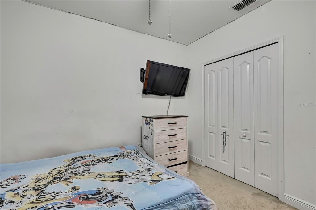 16197 Medrick Road Weeki Wachee, FL 34614 - Photo 16 of 22 a bedroom with a bed and a flat screen tv