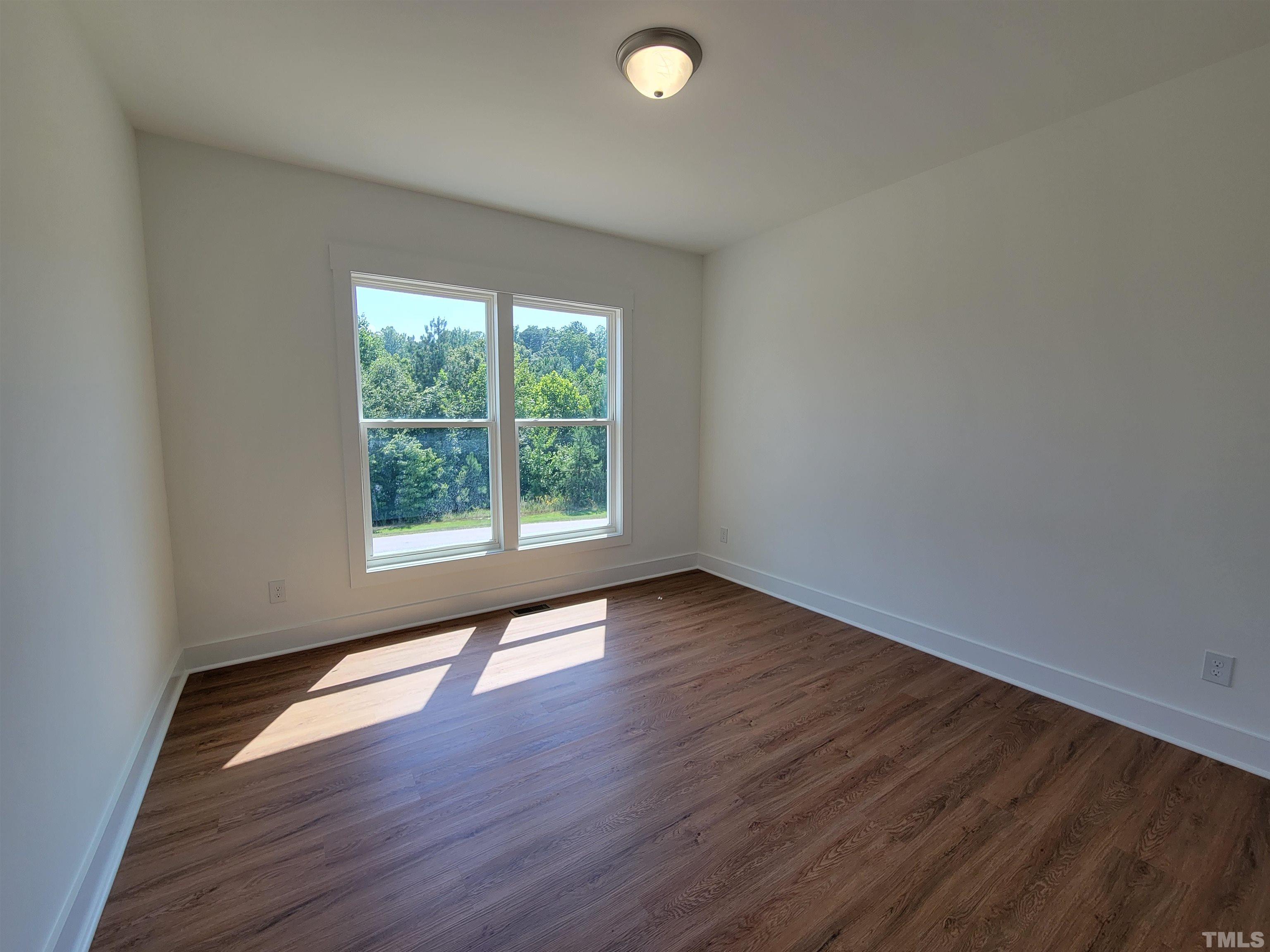 104 Glasgow Street Stem, NC 27581 - Photo 9 of 21 an empty room with wooden floor and windows