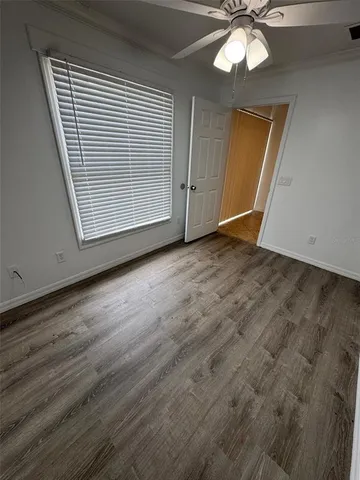 an empty room with wooden floor cabinet and windows