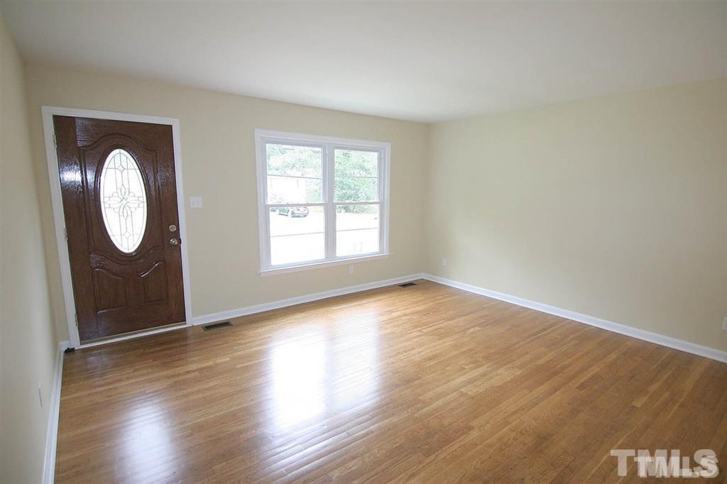 556 Dacian Road Raleigh, NC 27610 - Photo 4 of 20 an empty room with wooden floor and mirror