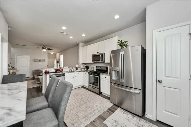 a kitchen with stainless steel appliances granite countertop a refrigerator a stove a sink a dining table and chairs