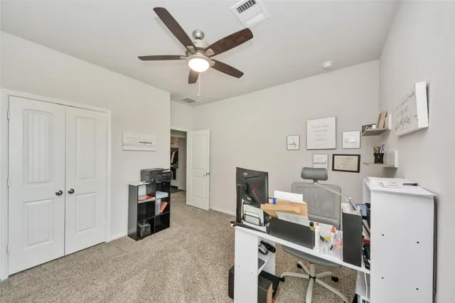 a view of a workspace with furniture and a ceiling fan