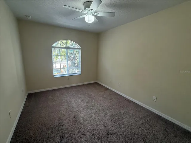 an empty room with a window and a fan