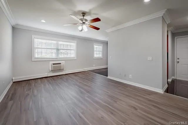 an empty room with wooden floor chandelier fan and windows