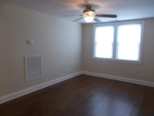 a view of an empty room with wooden floor and a window