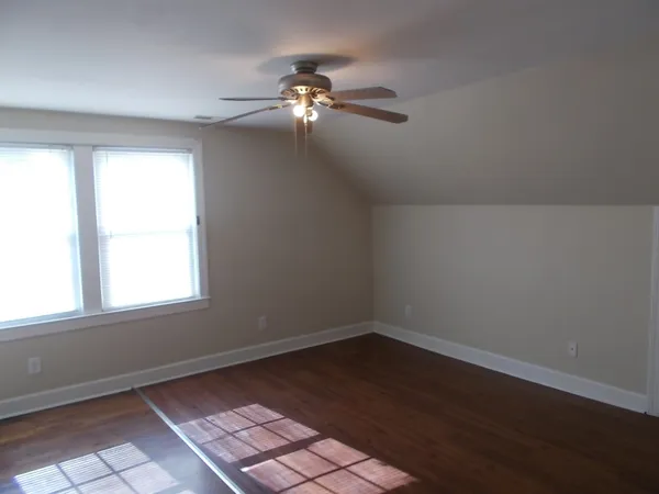 an empty room with wooden floor chandelier fan and closet area