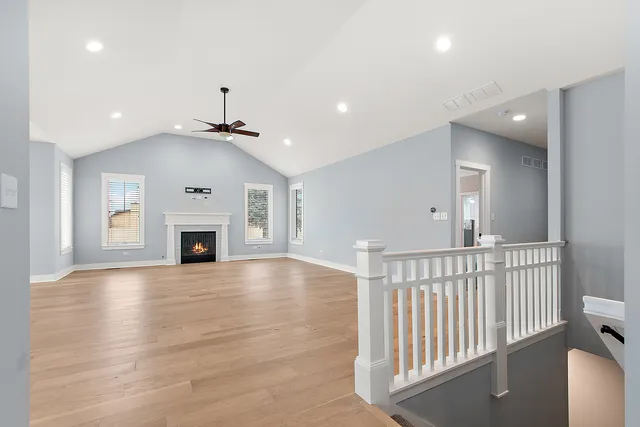 an empty room with wooden floor fireplace and windows