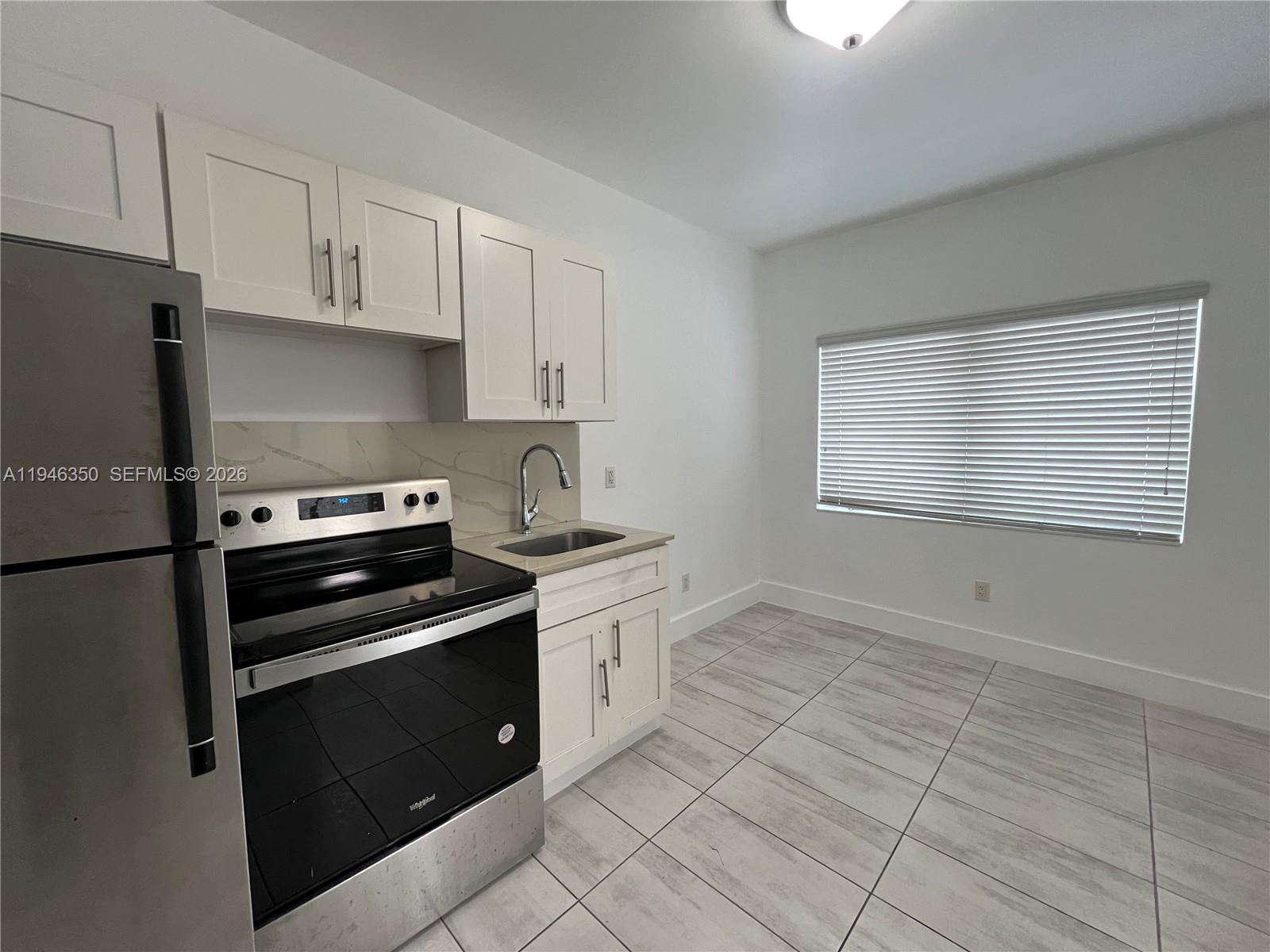 1201 Pennsylvania Avenue, Unit 204 Miami Beach, FL 33139 - Photo 1 of 8 a kitchen with granite countertop white cabinets and appliances