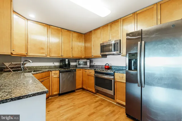 a kitchen with stainless steel appliances granite countertop a sink a stove and a refrigerator