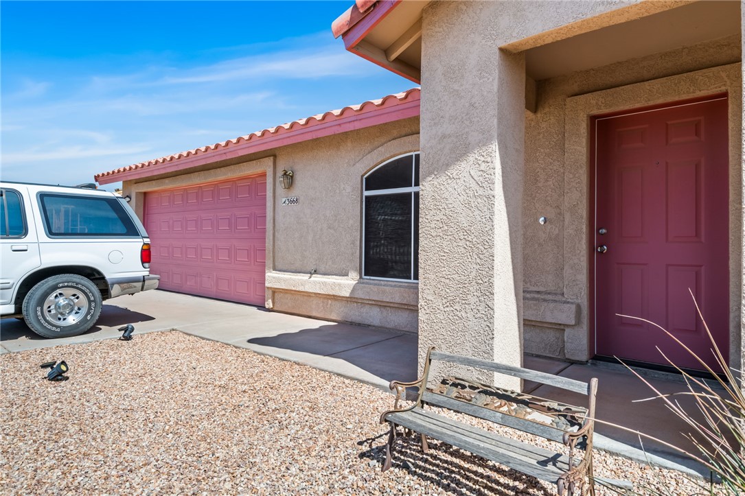 3668 North Neptune Road Golden Valley, AZ 86413 - Photo 6 of 38 The property features a stucco exterior with a tiled roof, a pink garage door, and a matching pink entry door