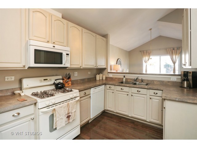 600 South Rosehall Lane Round Lake, IL 60073 - Photo 3 of 16 a kitchen with granite countertop white cabinets and white appliances