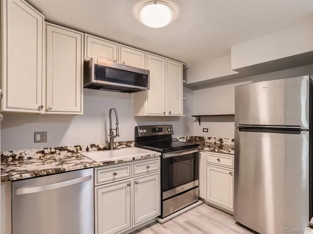 a kitchen with granite countertop a sink stove and refrigerator