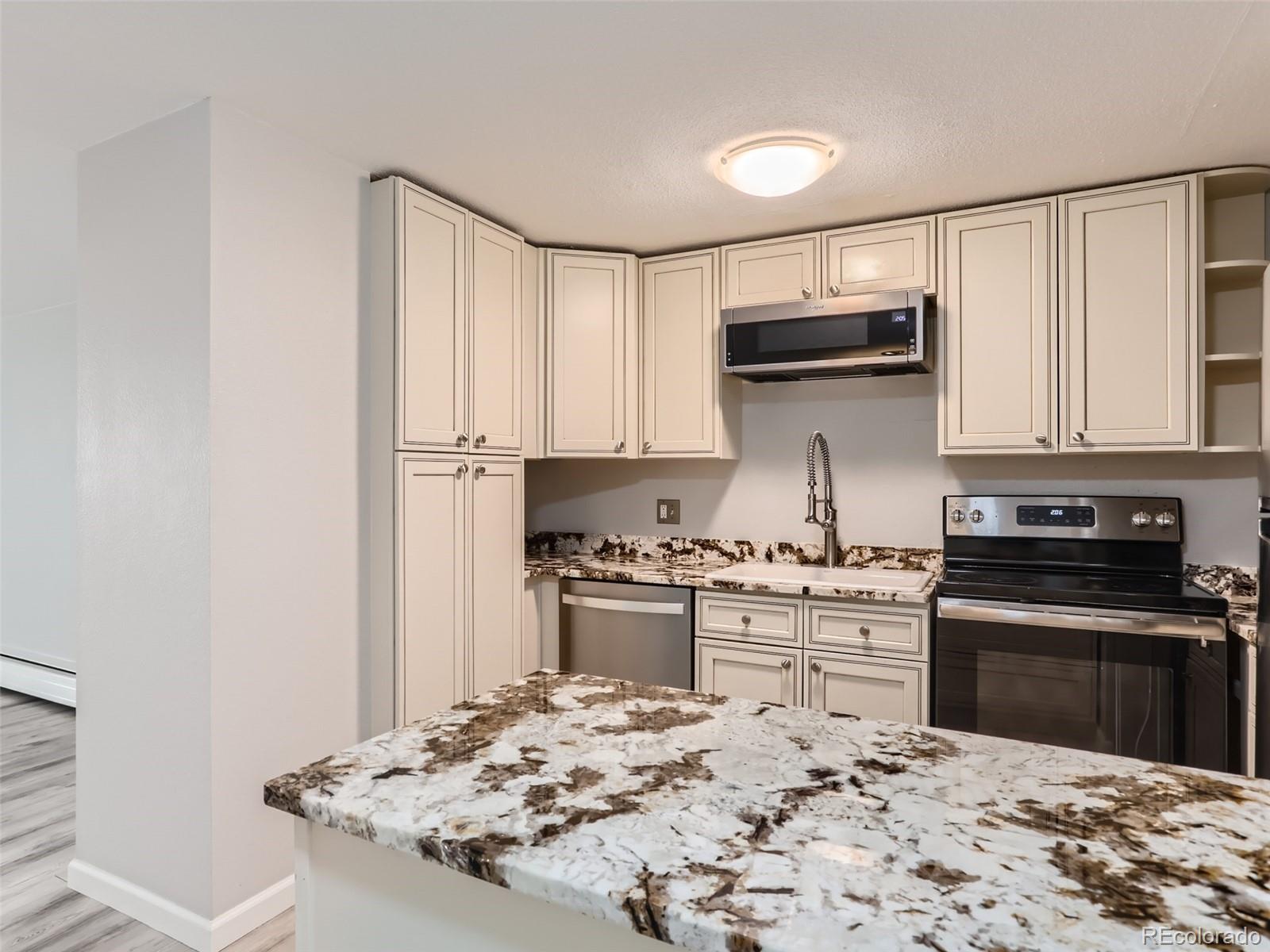 1029 East 8th Avenue, Unit 502 Denver, CO 80218 - Photo 5 of 26 a kitchen with kitchen island granite countertop a stove sink and cabinets