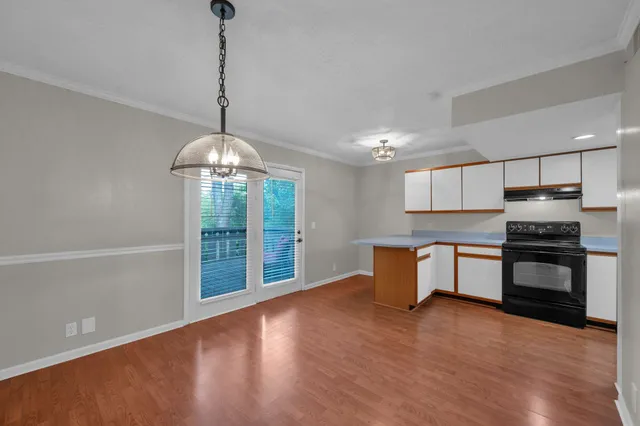 a kitchen with stainless steel appliances granite countertop a refrigerator a sink dishwasher a stove and a dining table with wooden floor