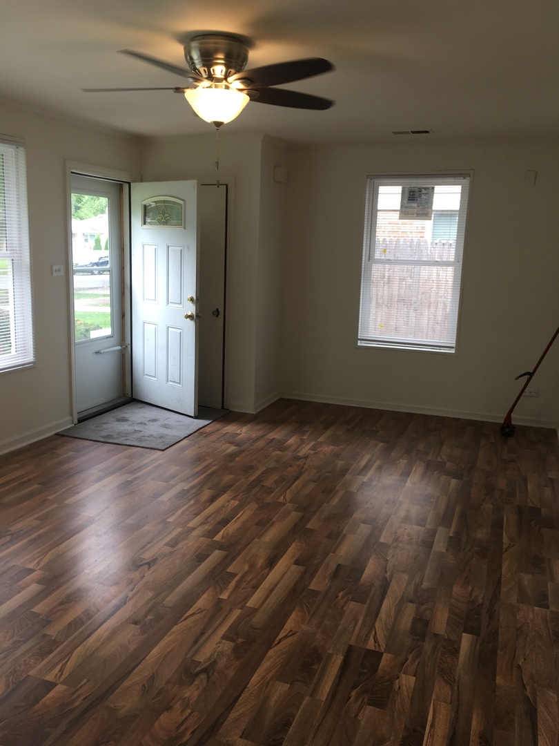 2144 Spruce Road Homewood, IL 60430 - Photo 4 of 13 an empty room with wooden floor chandelier fan and windows