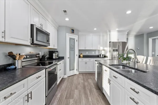 a kitchen with stainless steel appliances granite countertop a sink dishwasher stove top oven and refrigerator